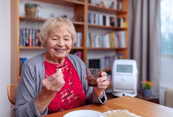 Old woman with water glass and medicine in hand